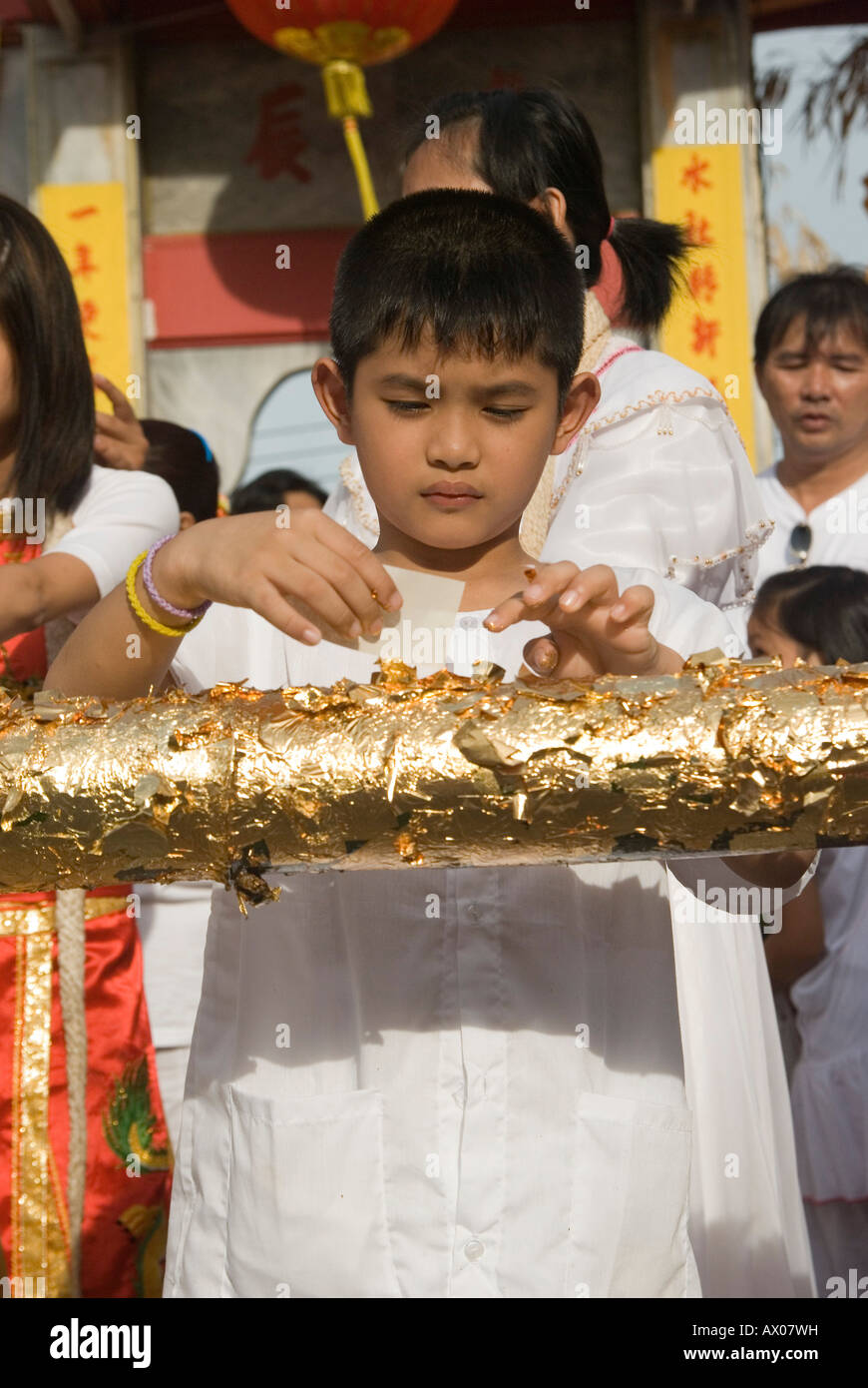Worshippers pray and place gold leaf before the flag pole raising