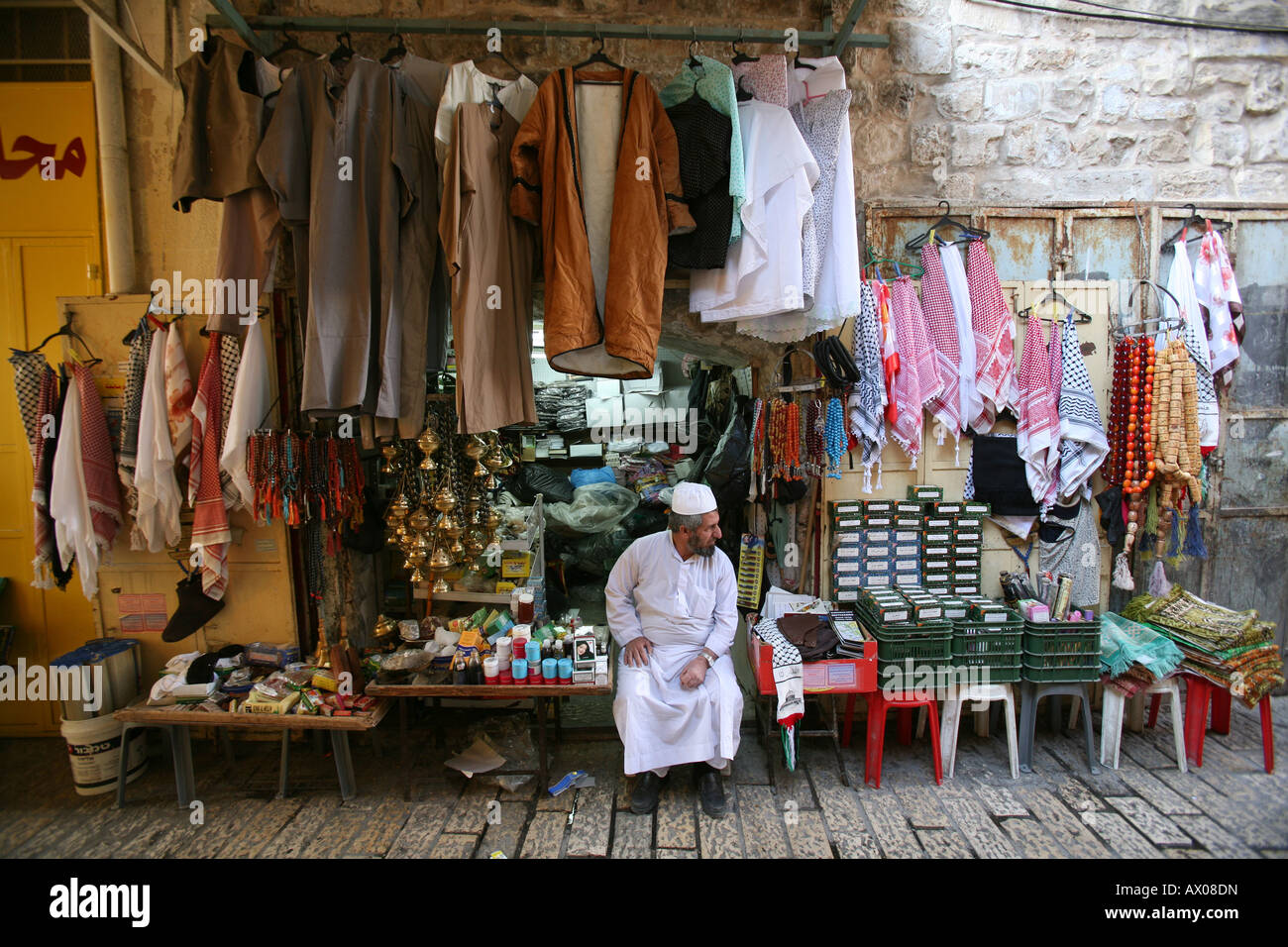 A vendors sits outside his stand at a market in the old city section of Jerusalem Stock Photo