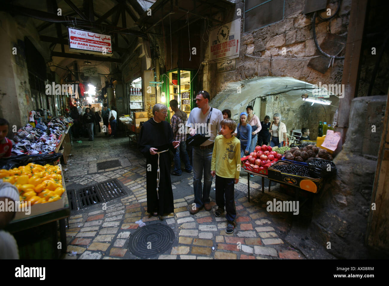 A clergyman talks to tourists at a market in the old city section of Jerusalem Stock Photo