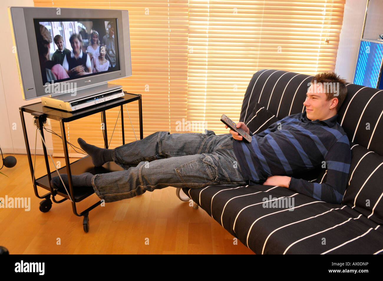 Teenager sitting on couch  watching  TV  Stock Photo 