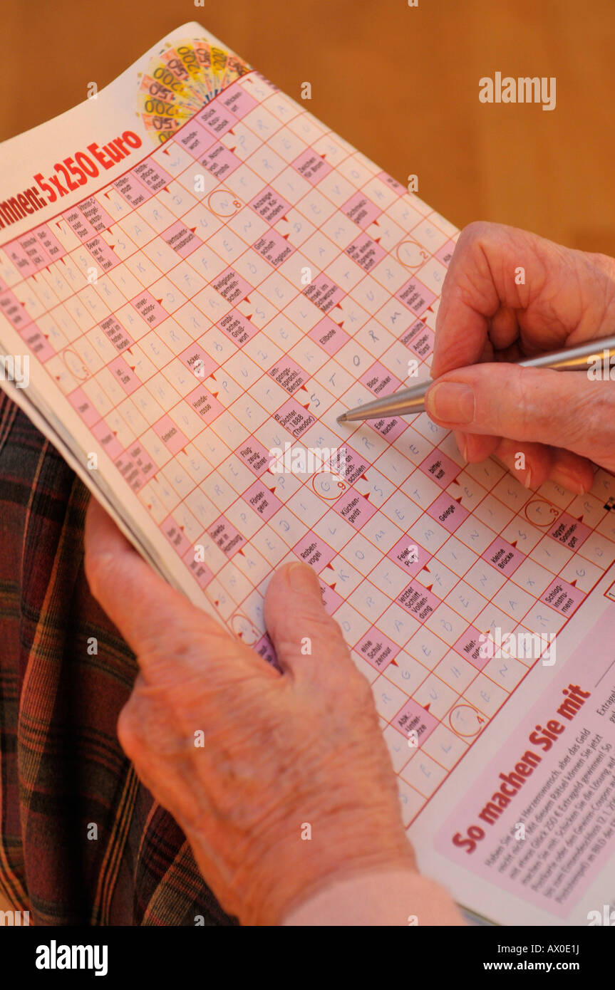 Elderly woman doing a crossword puzzle, close-up shot Stock Photo