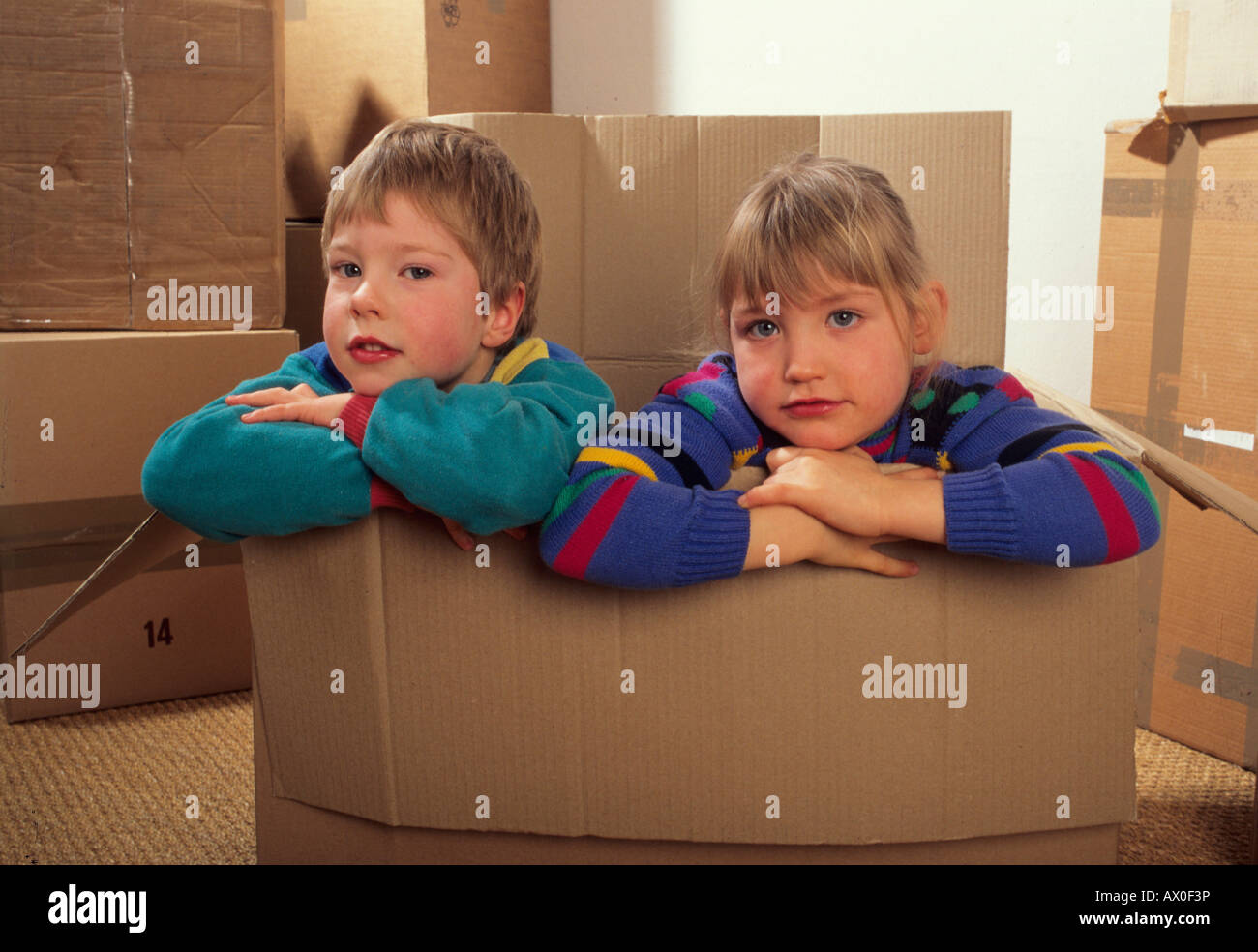 Boy and girl sitting in a cardboard box Stock Photo