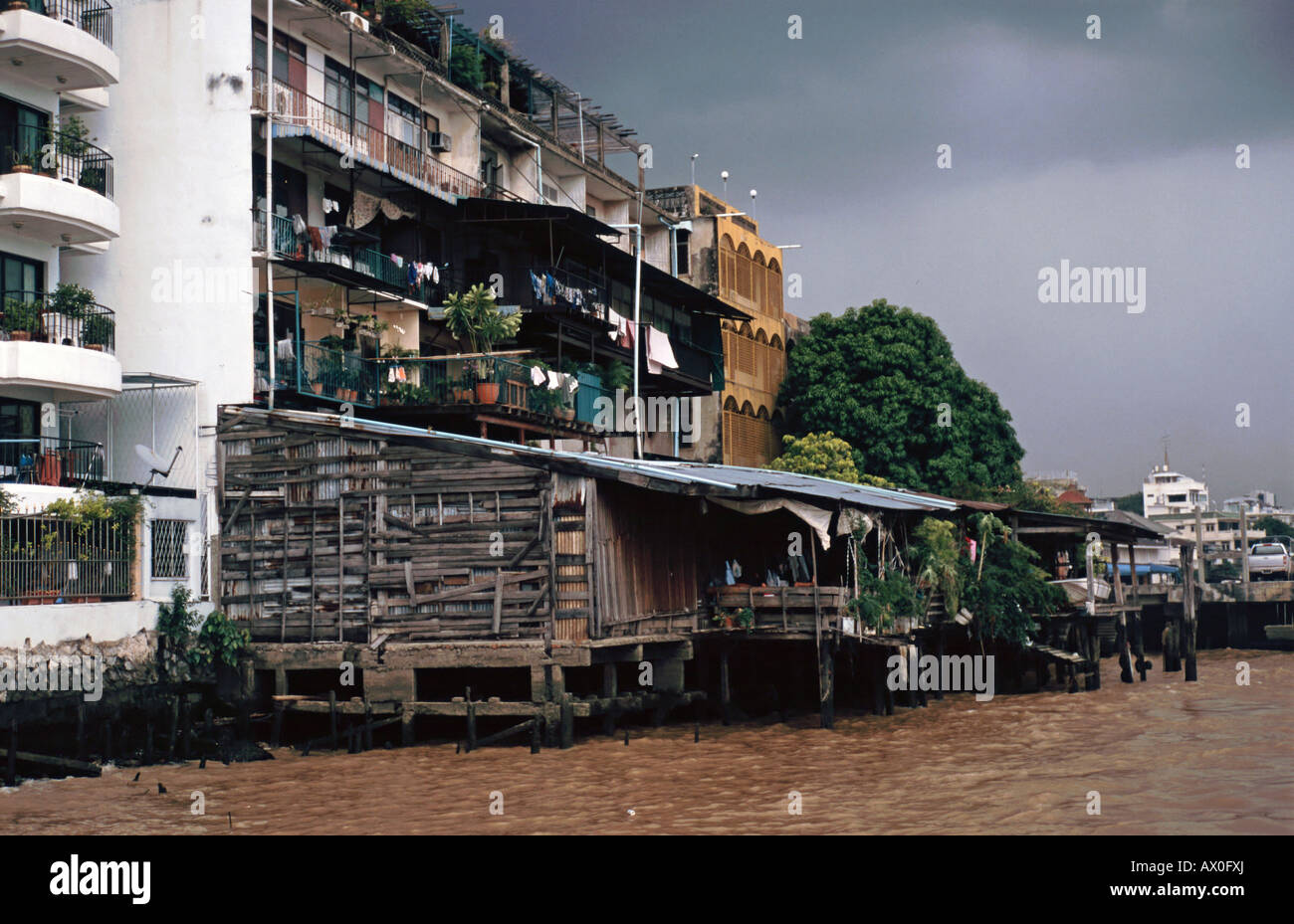 Apartments and miserable wooden huts at the Mae Nam Chao Praya River, Bangkok, Thailand Stock Photo