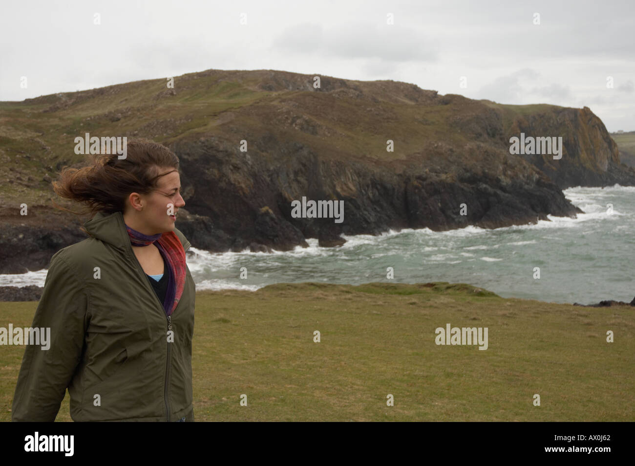 Girl standing in the wind on a cliff, South Coast of Cornwall, Kynance Cove Stock Photo