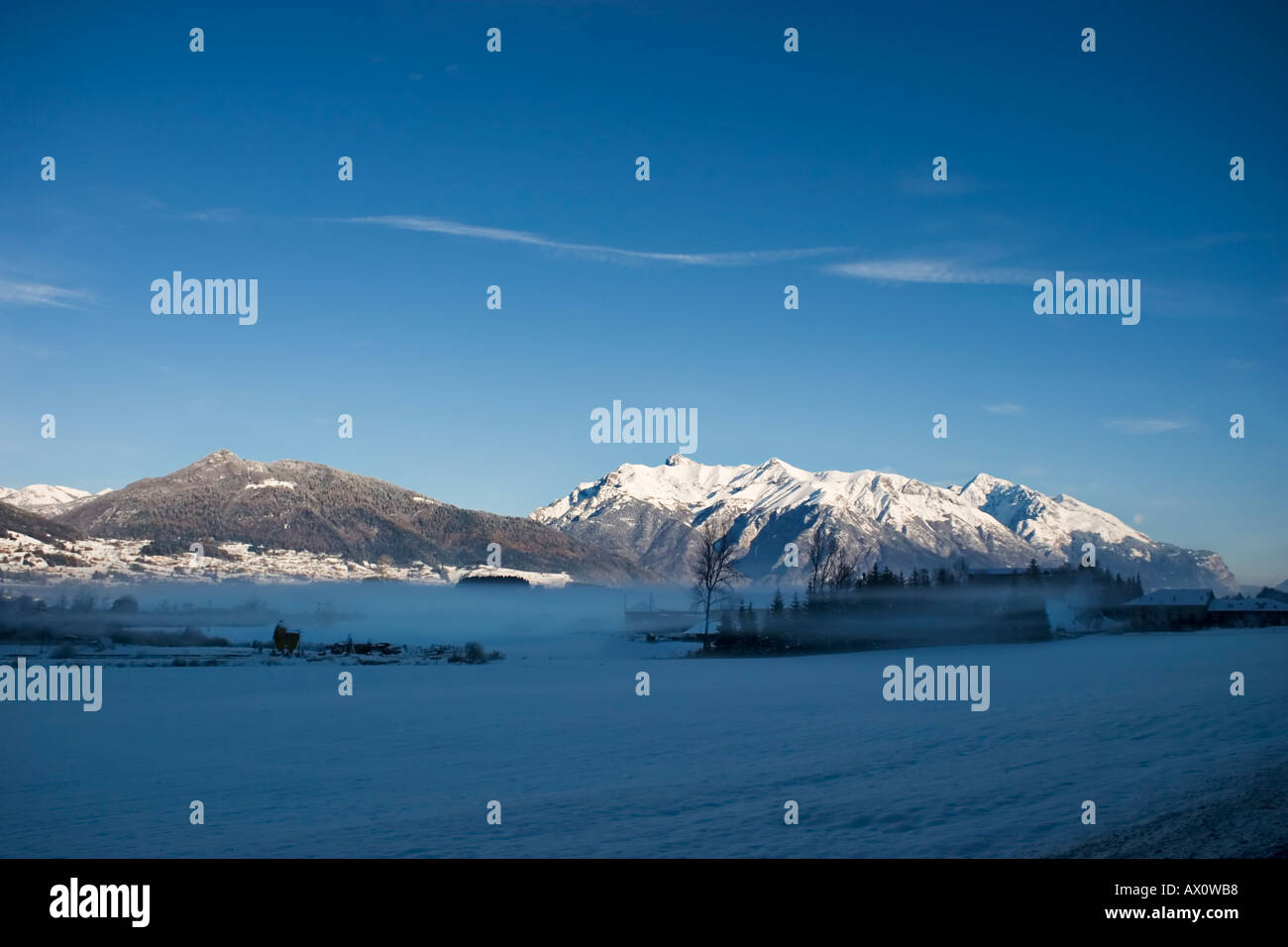 panorarama lanscape mountain in winter with low fog and small farm smoth blue sky and smallnes cloud Stock Photo