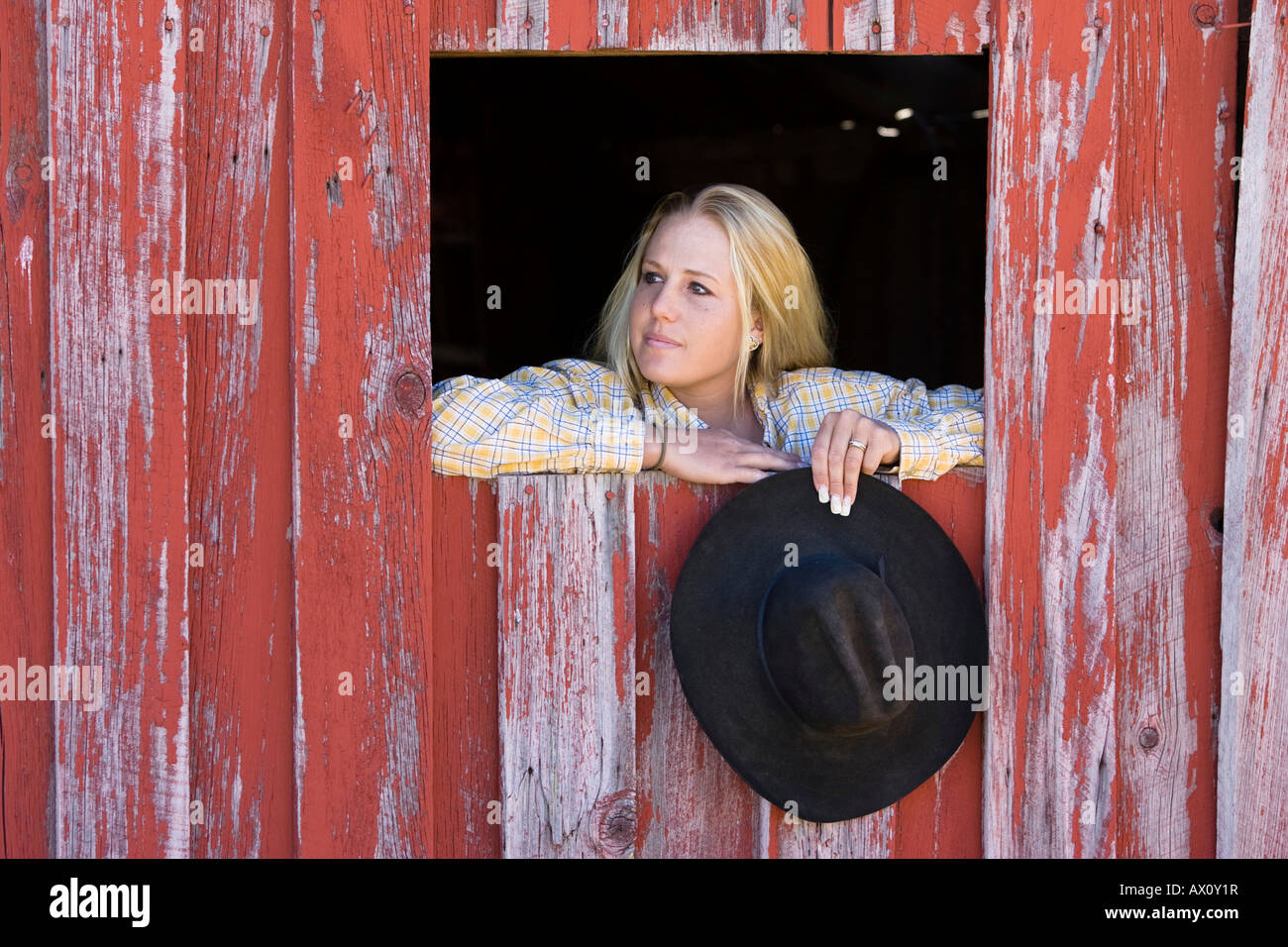 Cowgirl looking out of barn-window, wildwest, Oregon, USA Stock Photo