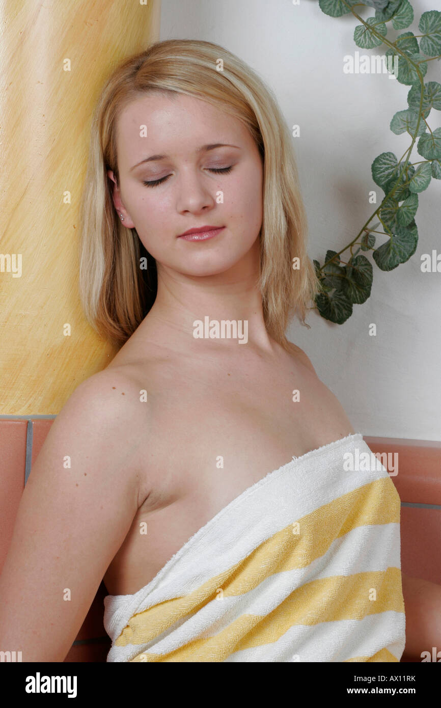 Woman wrapped in a towel relaxes at spa, eyes shut Stock Photo