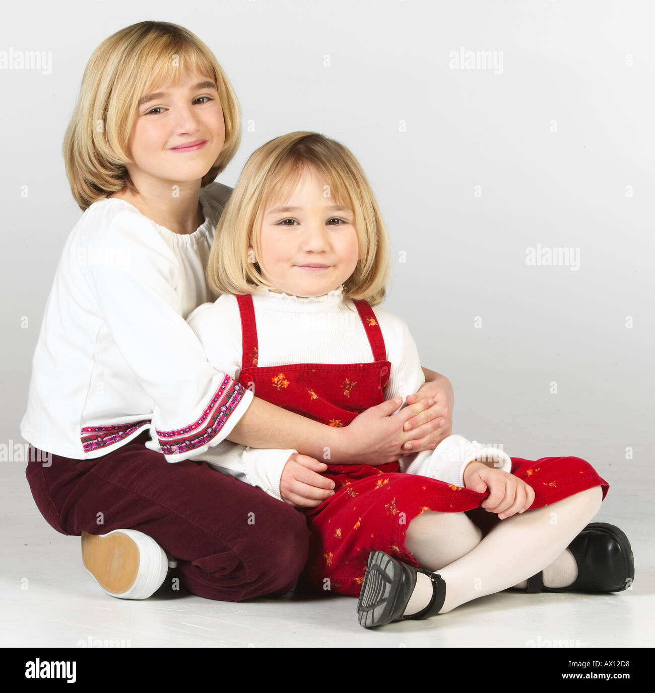 Two blonde girls sitting cross legged on the floor Stock Photo - Alamy