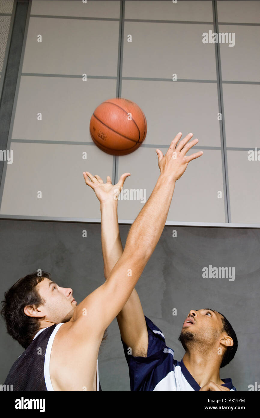 Two Basketball players reaching for a basketball Stock Photo