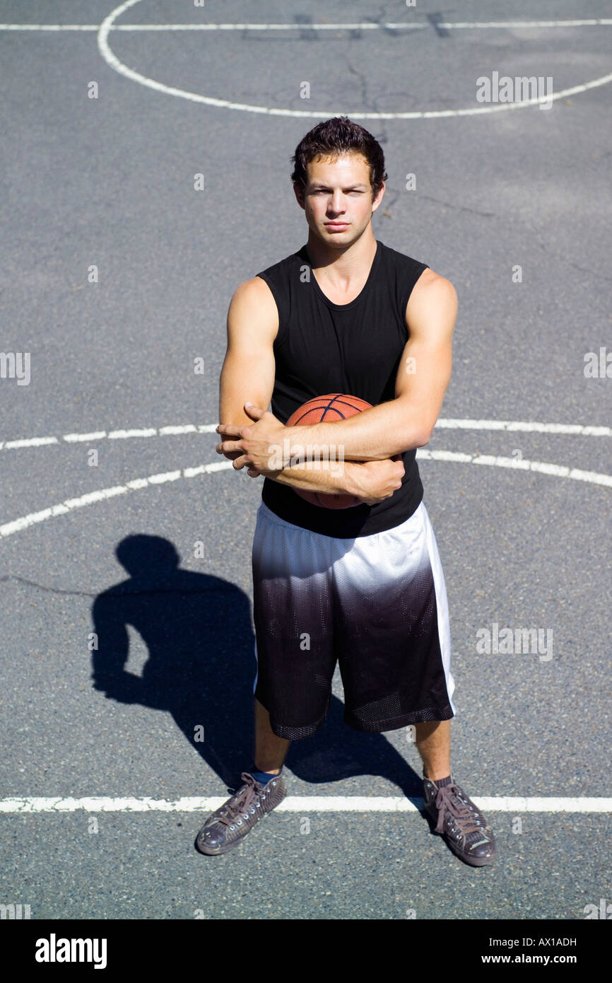 A young man standing on the free throw line at an outdoor basketball court Stock Photo
