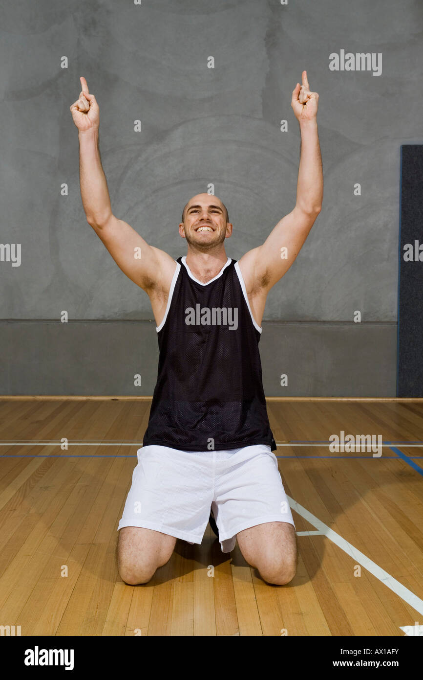 A young man kneeling with his arms raised in victory Stock Photo Alamy
