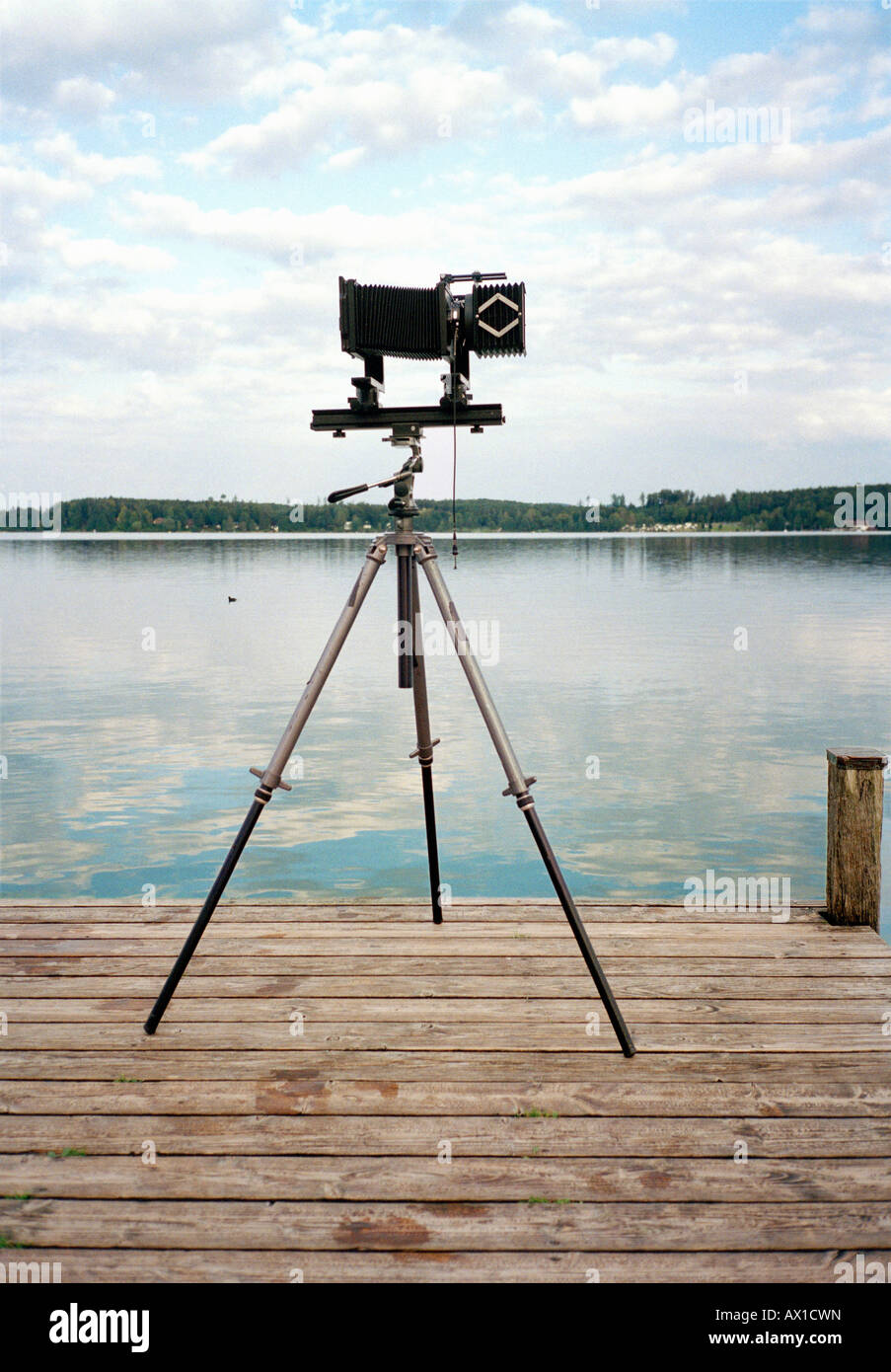 An old fashioned camera on a tripod in front of a lake Stock Photo