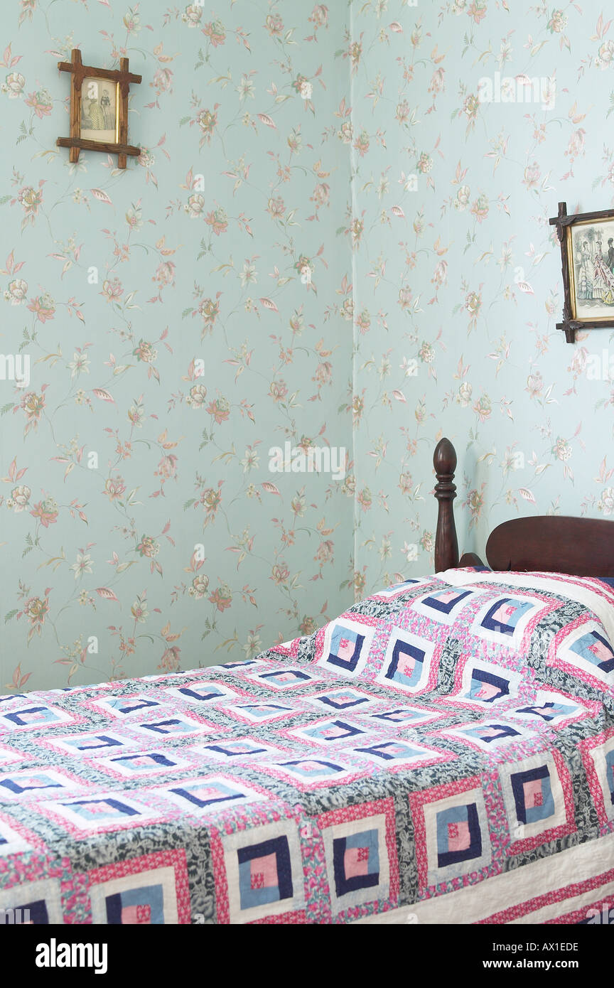 Bedroom With Patterned Wallpaper And A Quilt On The Bed