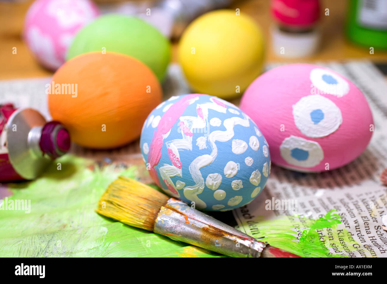 Painted Easter eggs on newspaper with tubes of paint and a paintbrush Stock Photo