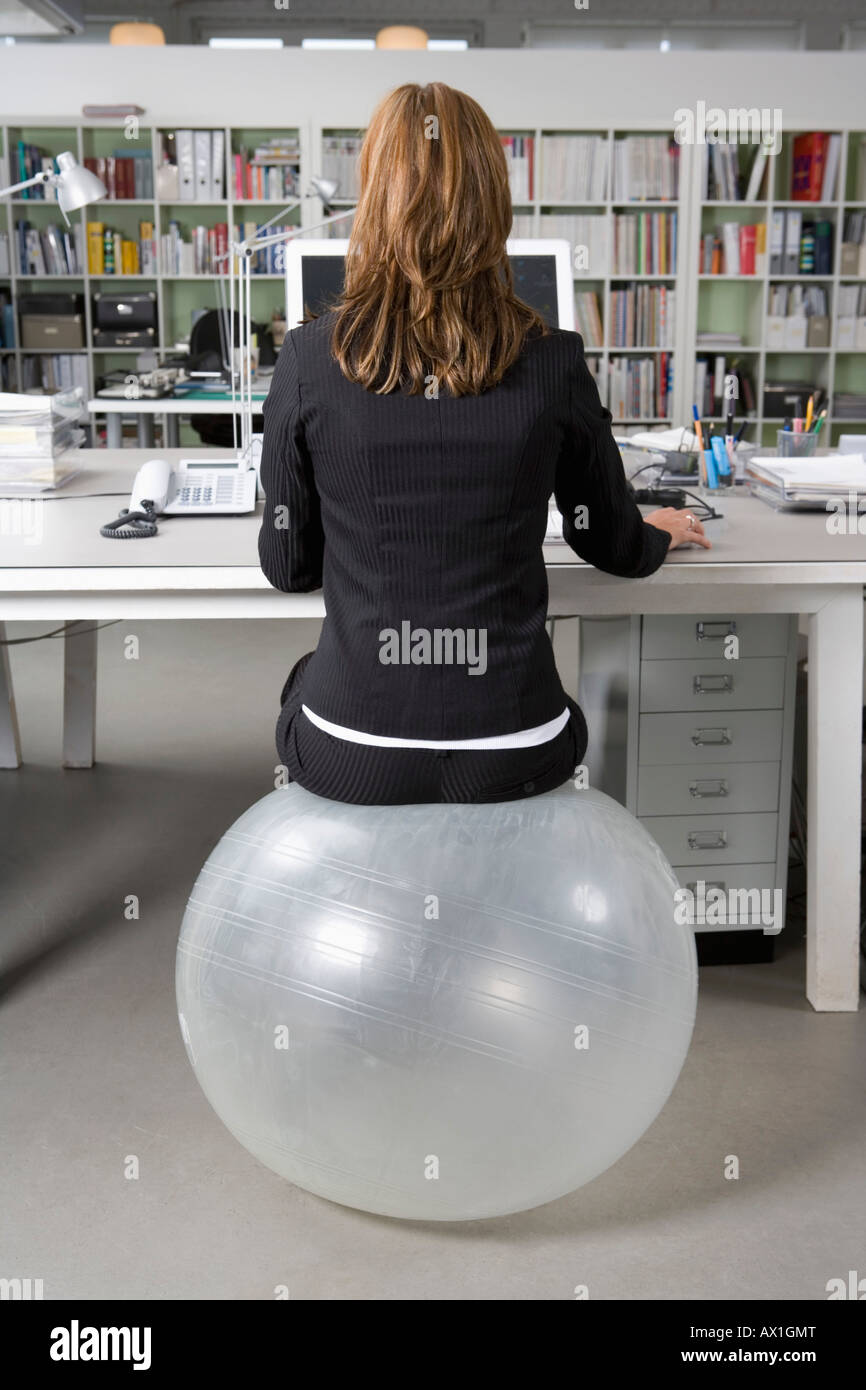 A woman sitting on an exercise ball at a desk in an office Stock Photo Alamy