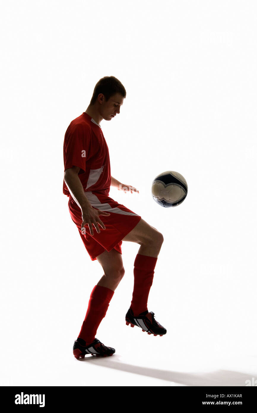 Studio shot of a soccer player bouncing a soccer ball on his knee Stock  Photo - Alamy