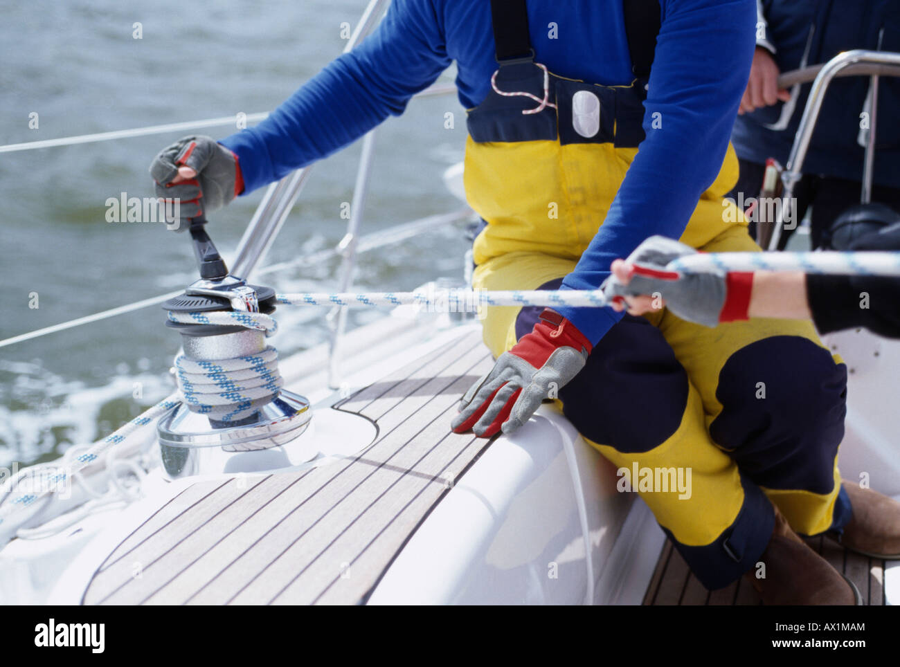 A person turning a cable winch on a yacht Stock Photo
