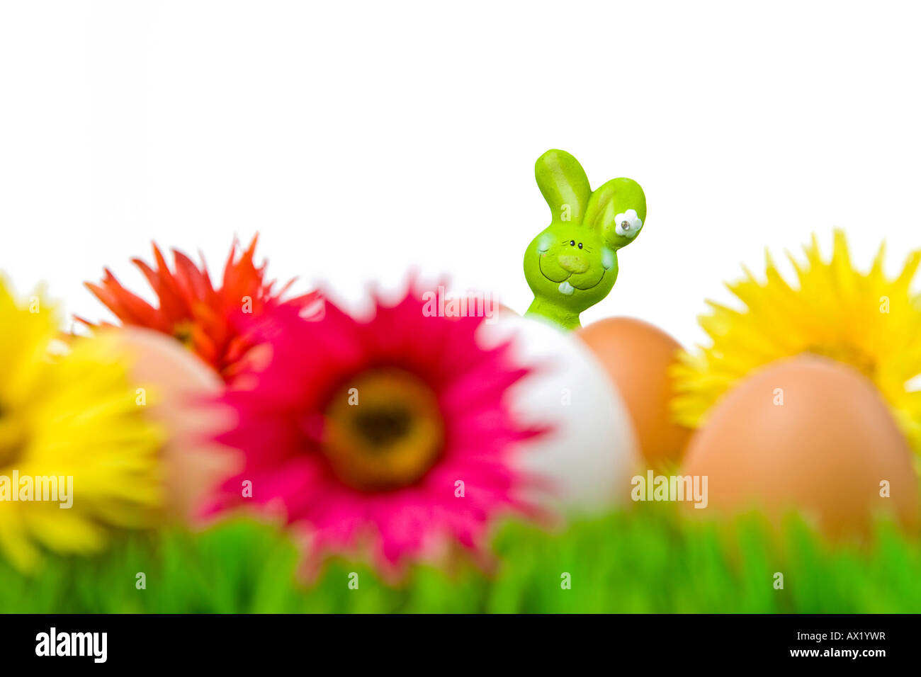 Easter bunny hiding behind eggs on a flower meadow Stock Photo
