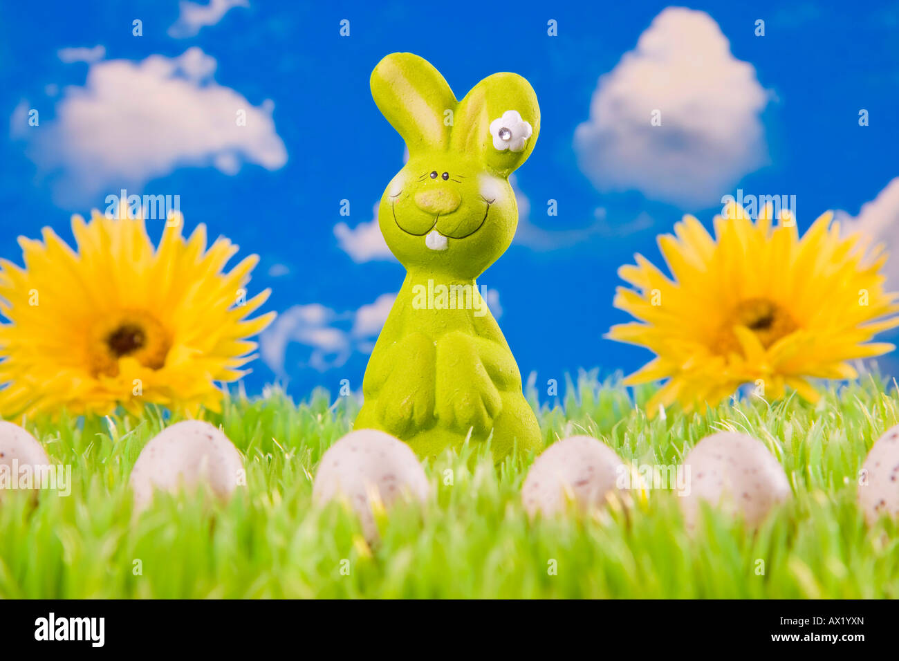 Easter bunny on meadow with Easter eggs in front of a blue cloudy sky Stock Photo