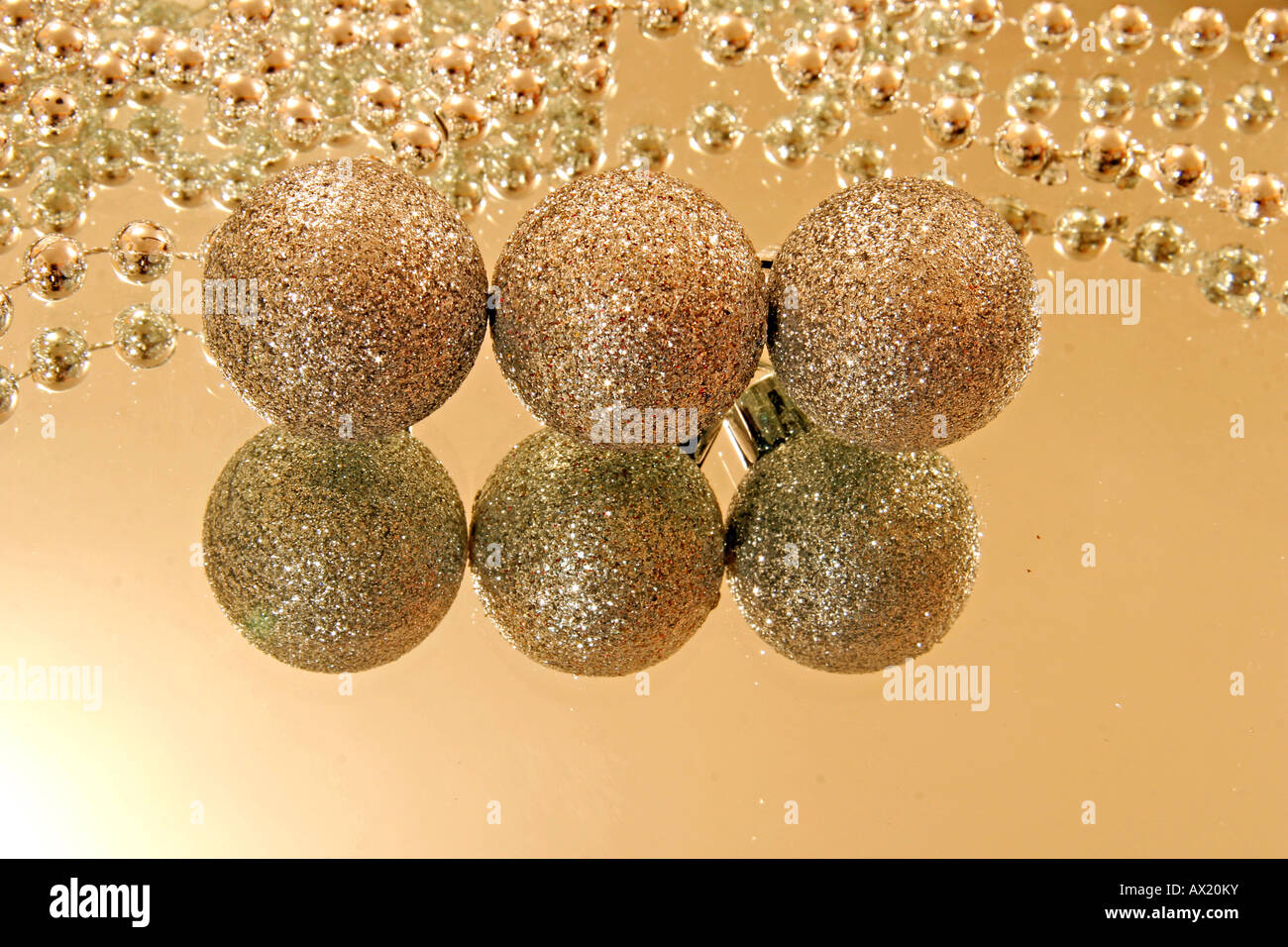 Three Christmas tree balls and pearl necklets on a mirror Stock Photo
