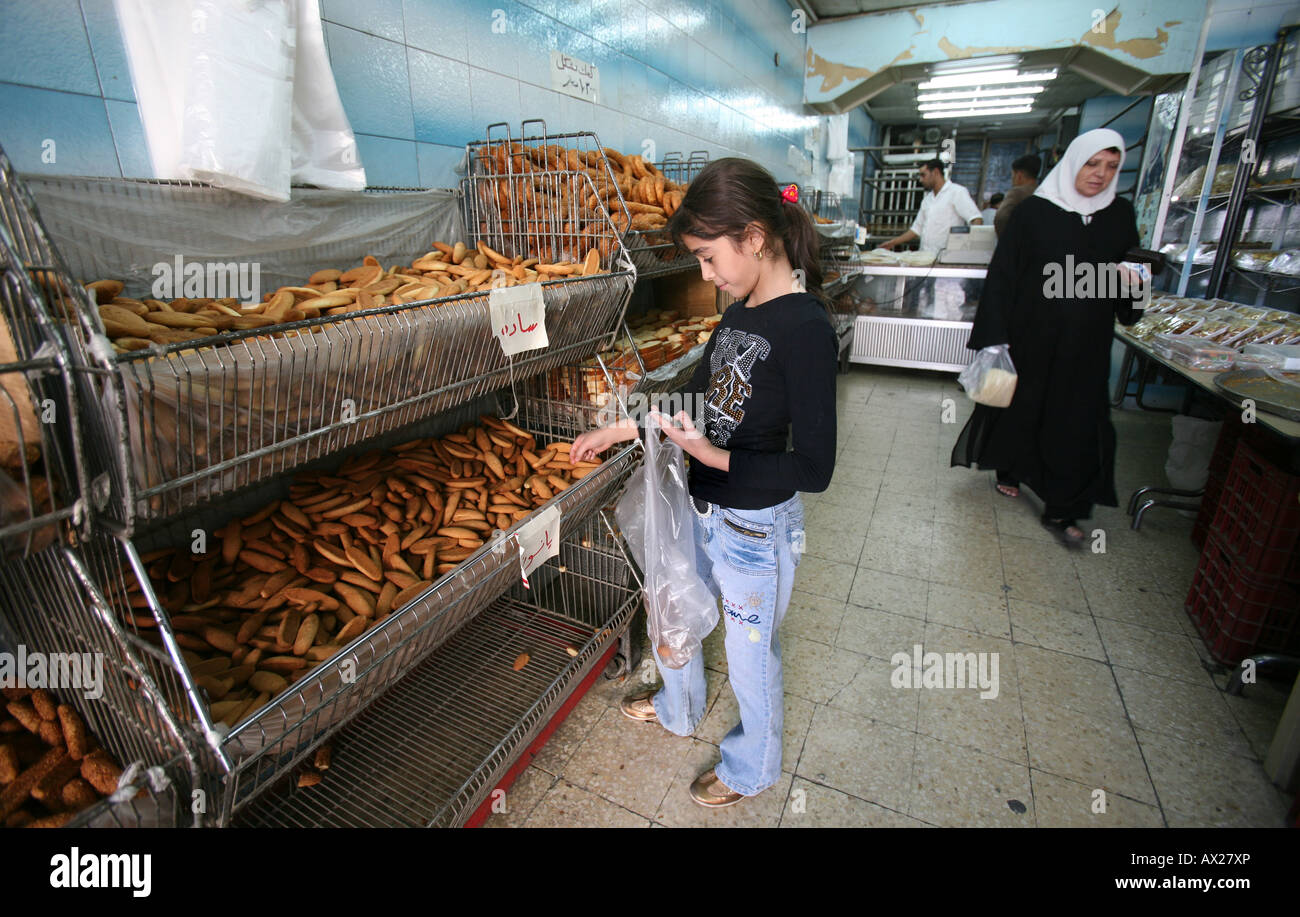 An Iraqi refugee girl buys bread for her famiy Many Iraqi refugees have settled in Amman Jordan because of the ongoing violence Stock Photo