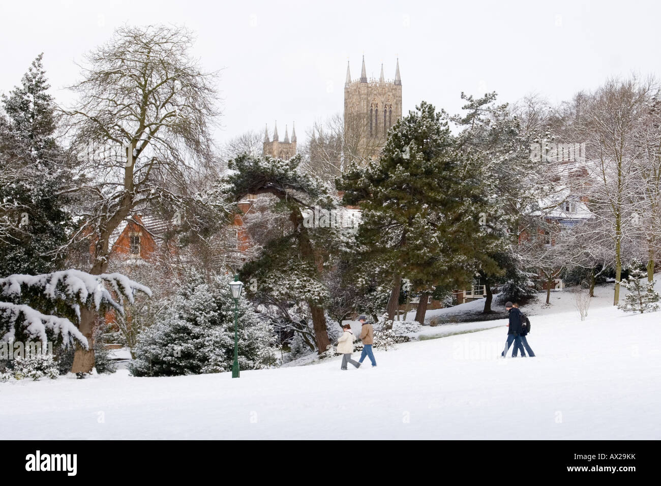 View of Lincoln cathedral from the Arboretum on a snowy winter day with people walking past Stock Photo