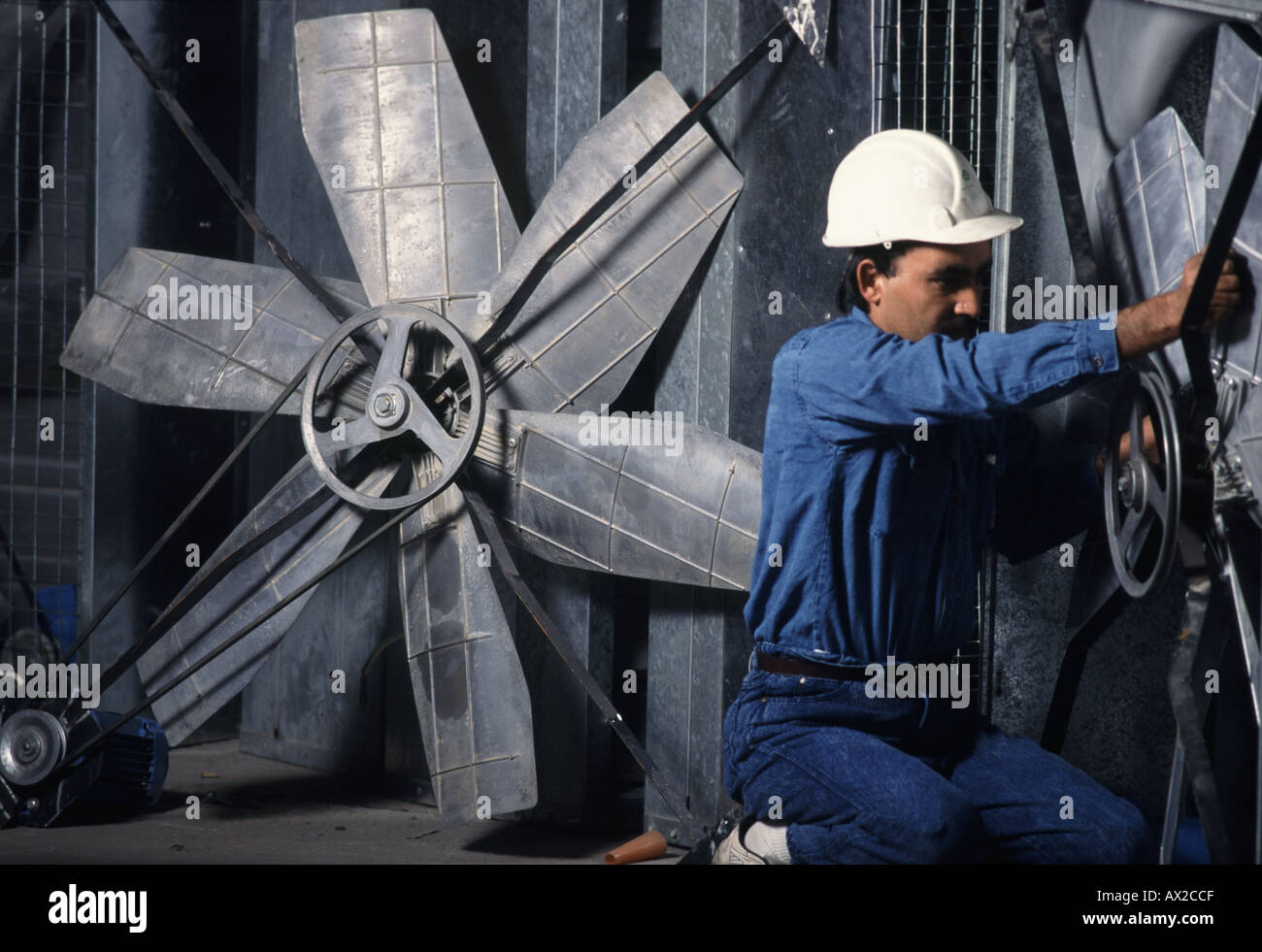 Engineer adjusts large fan used for greenhouses in Saudi Arabia Stock Photo
