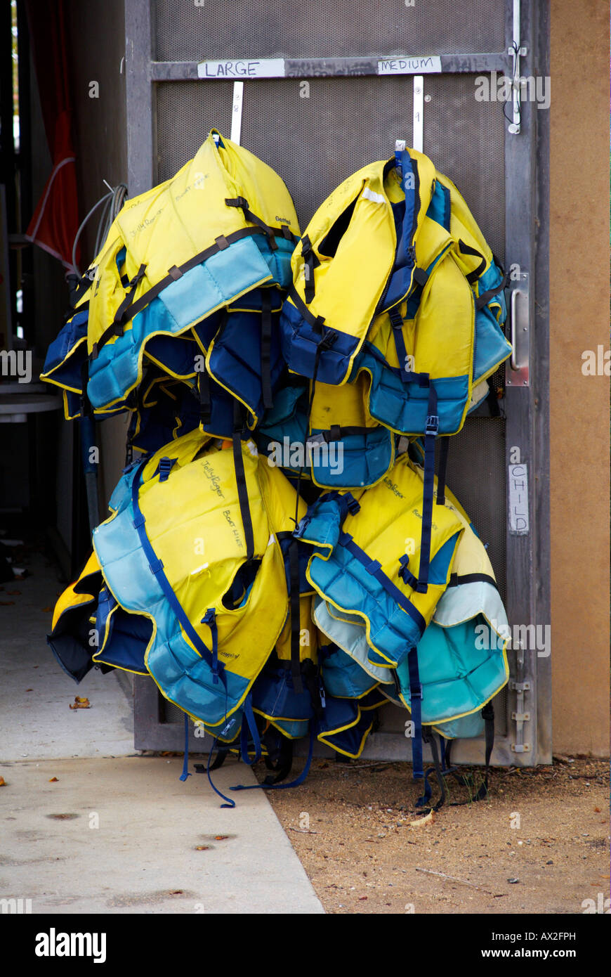 Life jackets hanging from the back of a door ready for use. Stock Photo