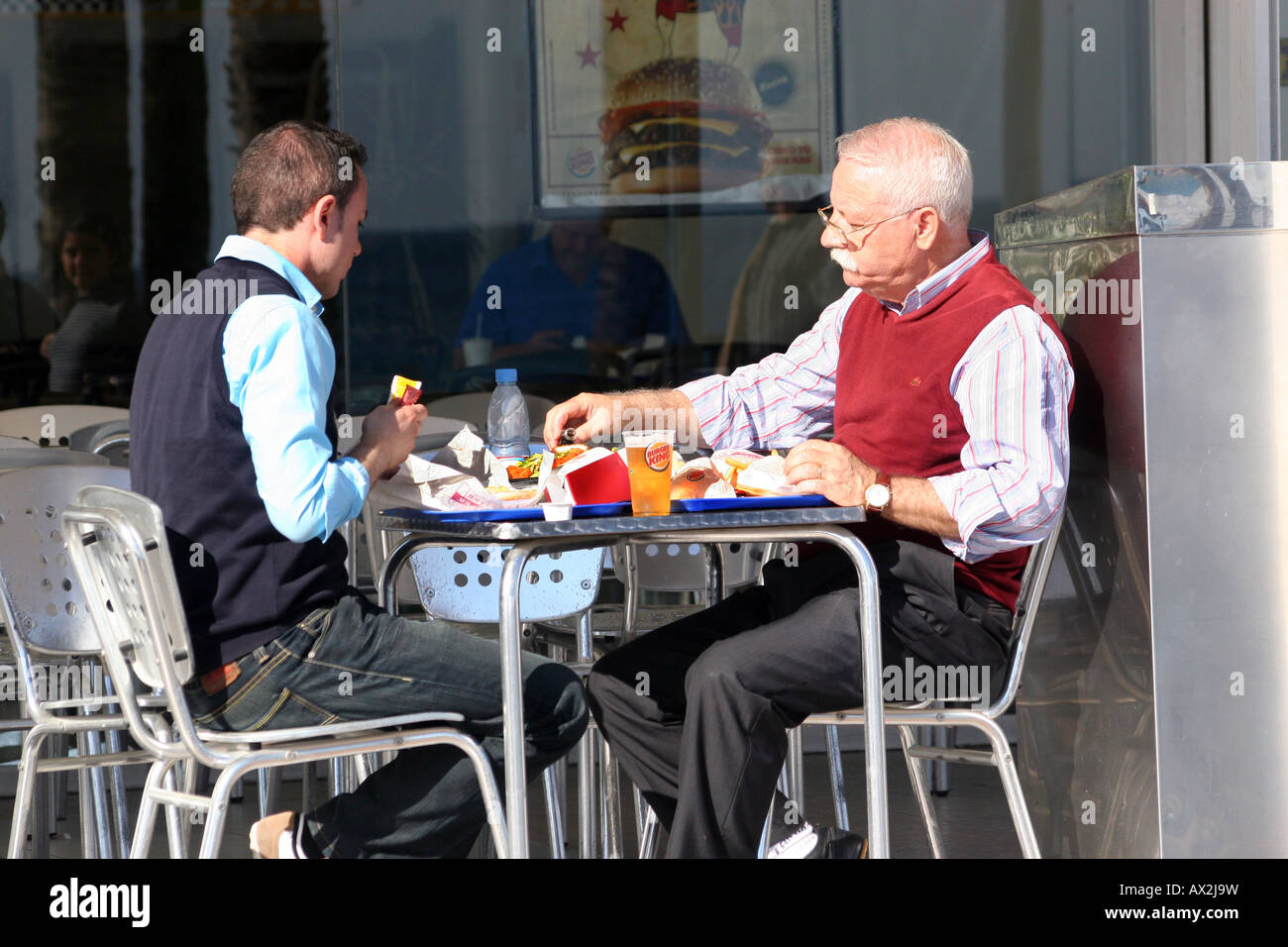 Two people eating and drinking outdoors at a table in Benidorm, Spain. Stock Photo