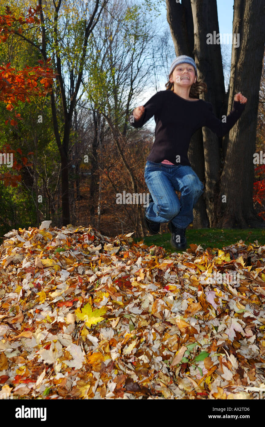 Smiling Young girl jumping in a pile of leaves in the Fall Toronto Stock Photo