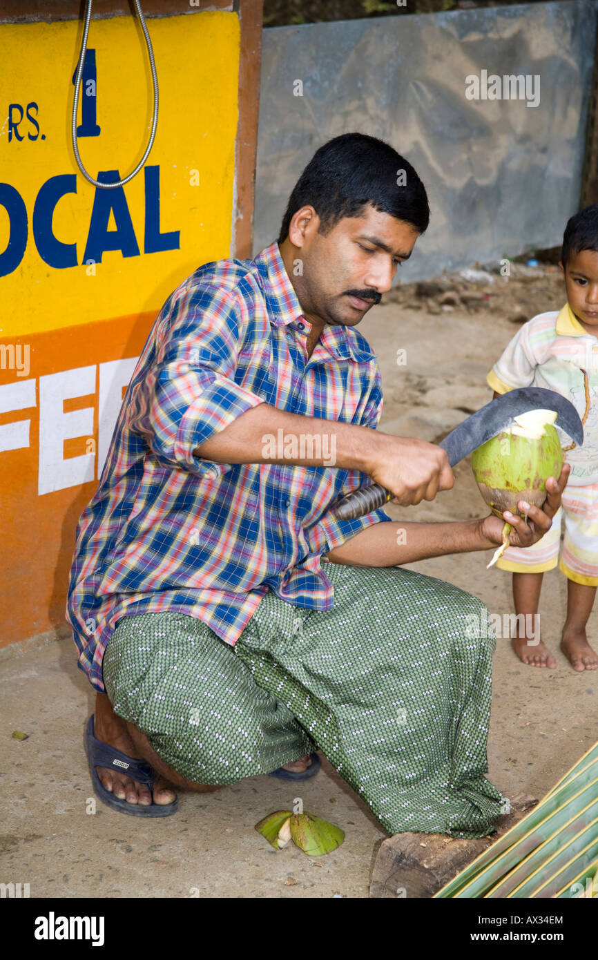 Man cutting a coconut with a large curved knife, Western Ghats, Kerala, India Stock Photo