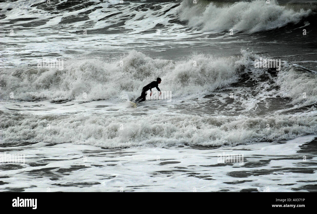 A SURFER IN FULL WETSUIT ENJOYS SURFING IN FEBRUARY IN CHALLABOROUGH BAY,NEAR BIGBURY ON SEA,ENGLAND,UK. Stock Photo