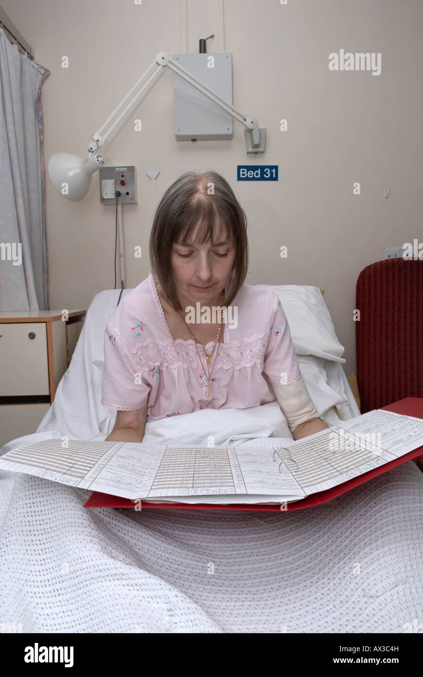 Female patient reading hospital notes in bed Stock Photo Alamy