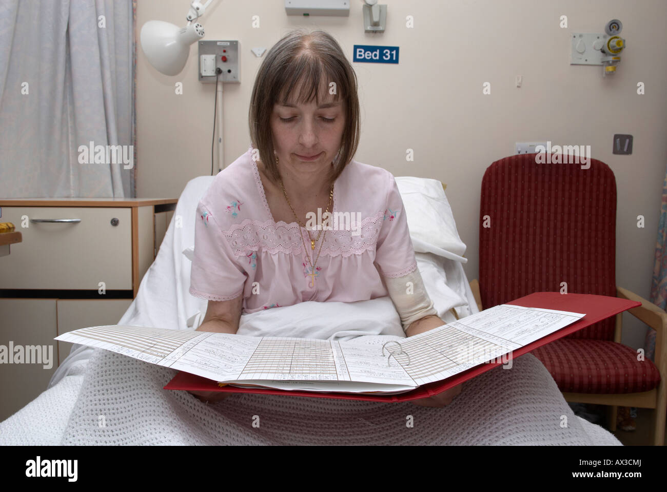 Female patient reading hospital notes in bed Stock Photo Alamy