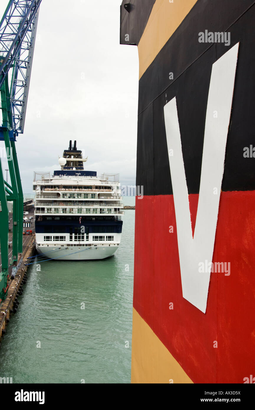 A ship funnel and shore container cranes contrast with a cruise ship at Lyttelton, New Zealand Stock Photo