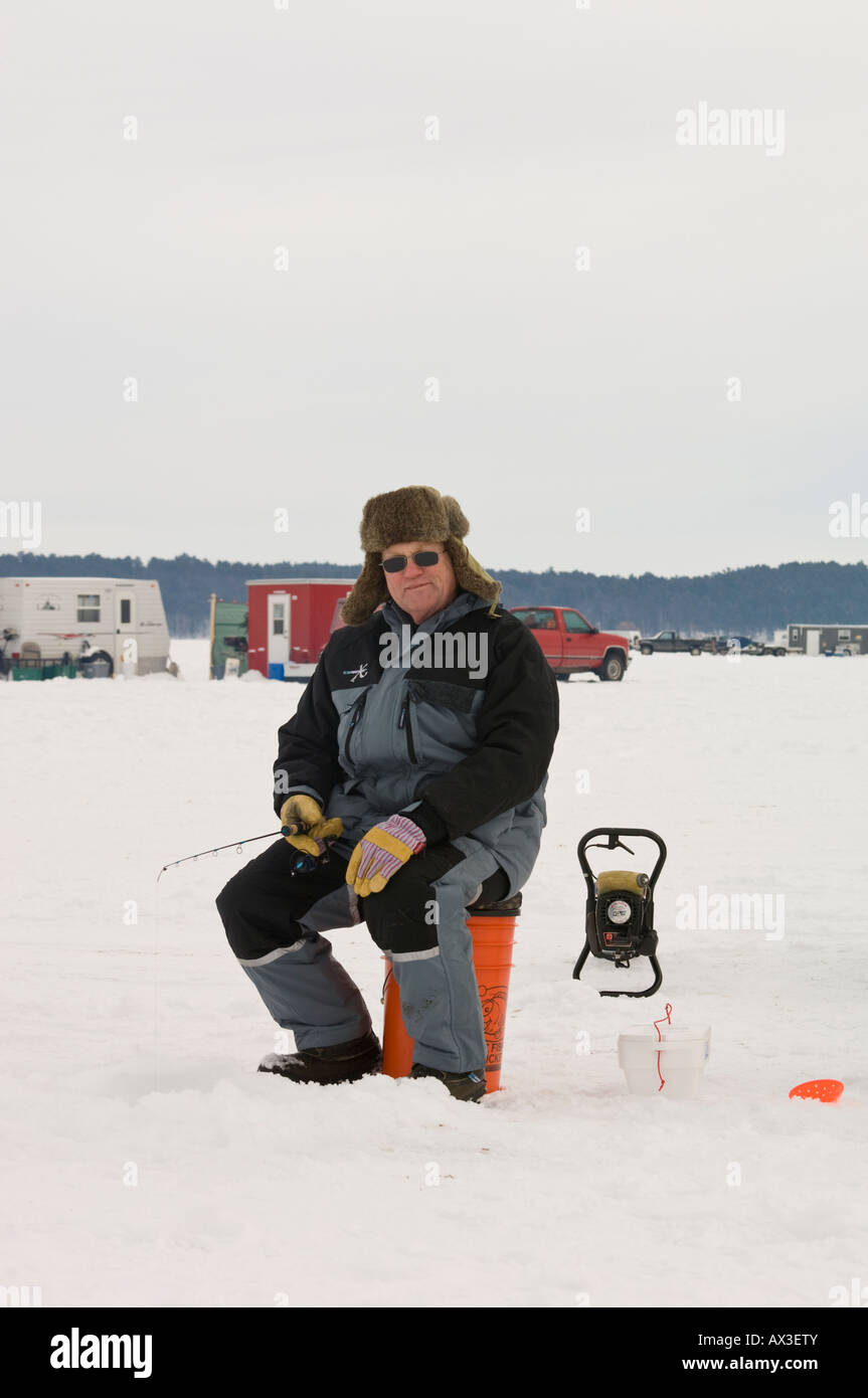 ICE FISHERMAN IN FUR HAT SITS ON A BUCKET ICE FISHING Stock Photo - Alamy