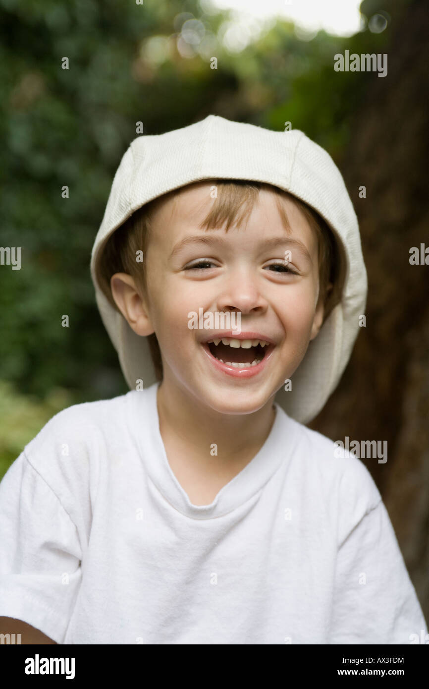 A young boy smiling and wearing a hat backwards Stock Photo
