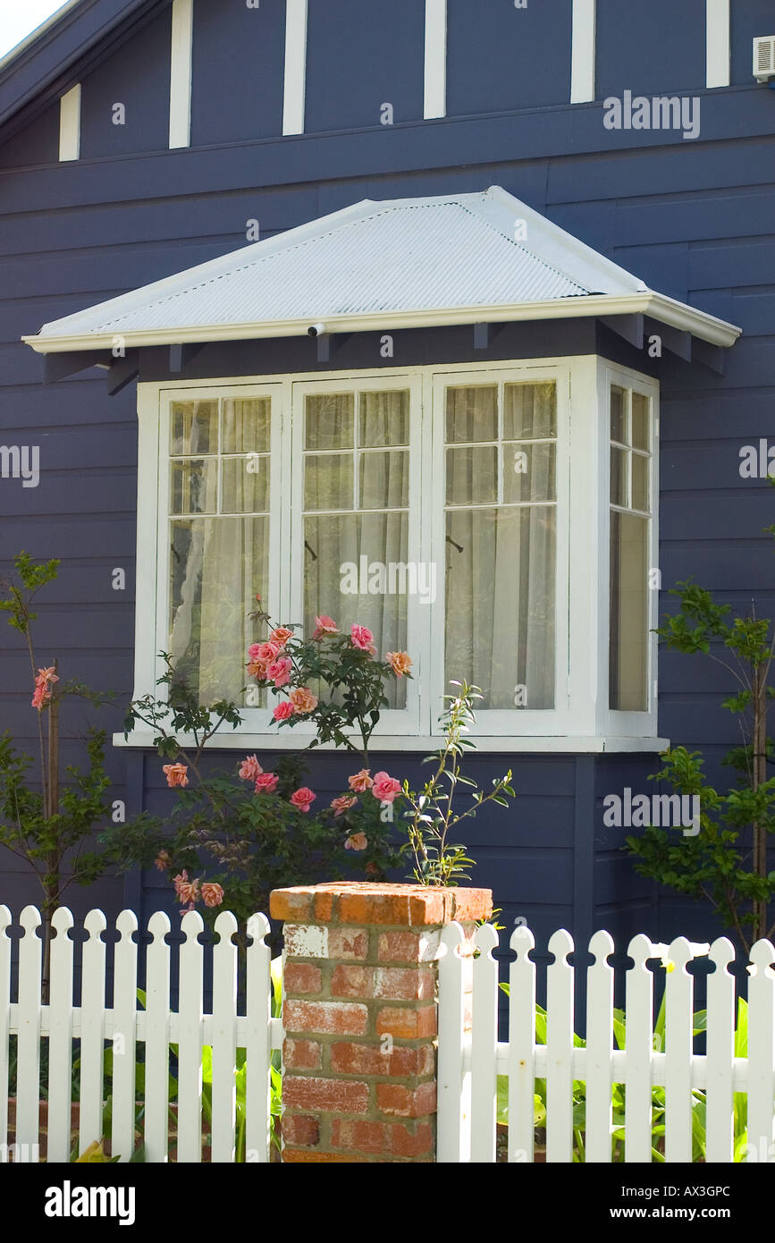 Cute bay window, white picket fence and roses on a typical suburban house Stock Photo