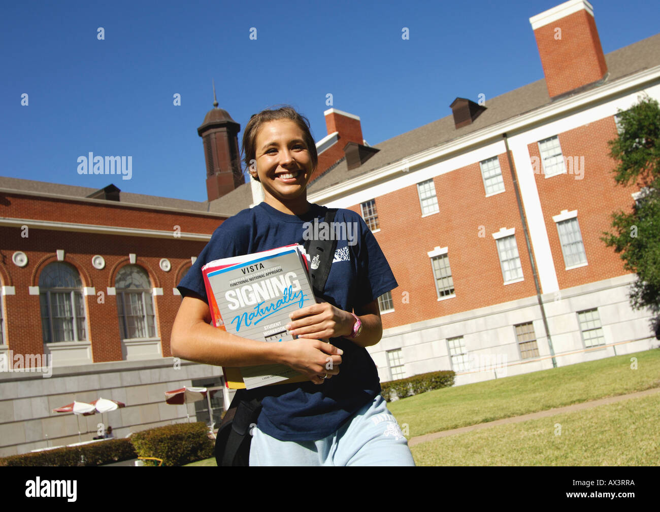 View of a young woman holding her books and smiling at the camera Stock ...