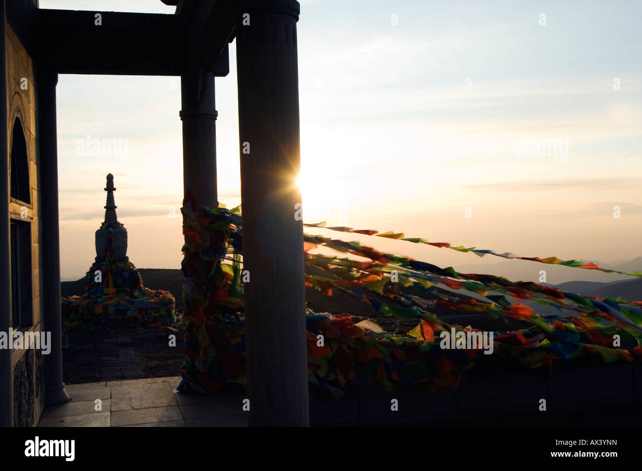 China, Shanxi Province, Wutaishan. Sunrise on a monastery stupa and prayer flags on Yedou Peak (3058m) at Wutaishan. Stock Photo