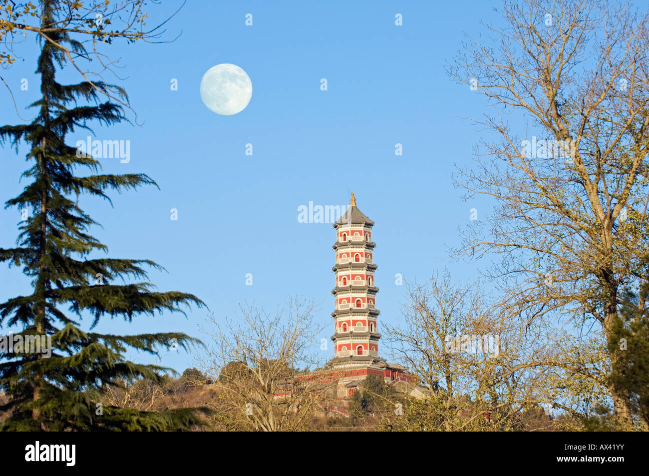 China, Beijing. A full moon rising over a pagoda on the grounds of