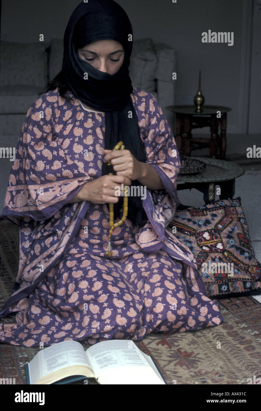 A Shi'ite woman reading the Qur'an and holding prayer beads Stock Photo