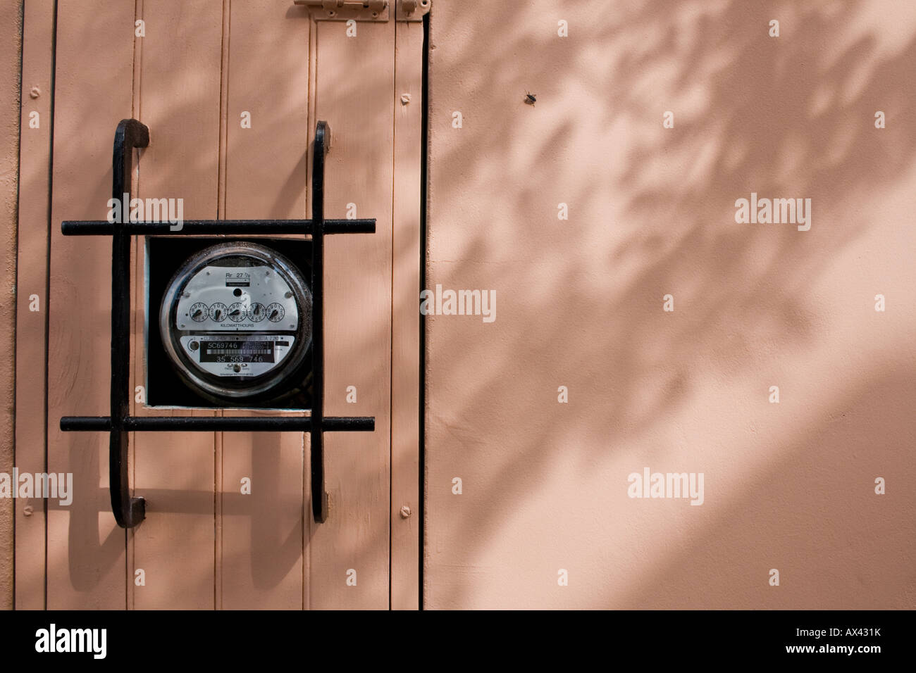 An electric usage metre behind a metal grate in the shadows on a sunny day in St. Augustine, Florida Stock Photo