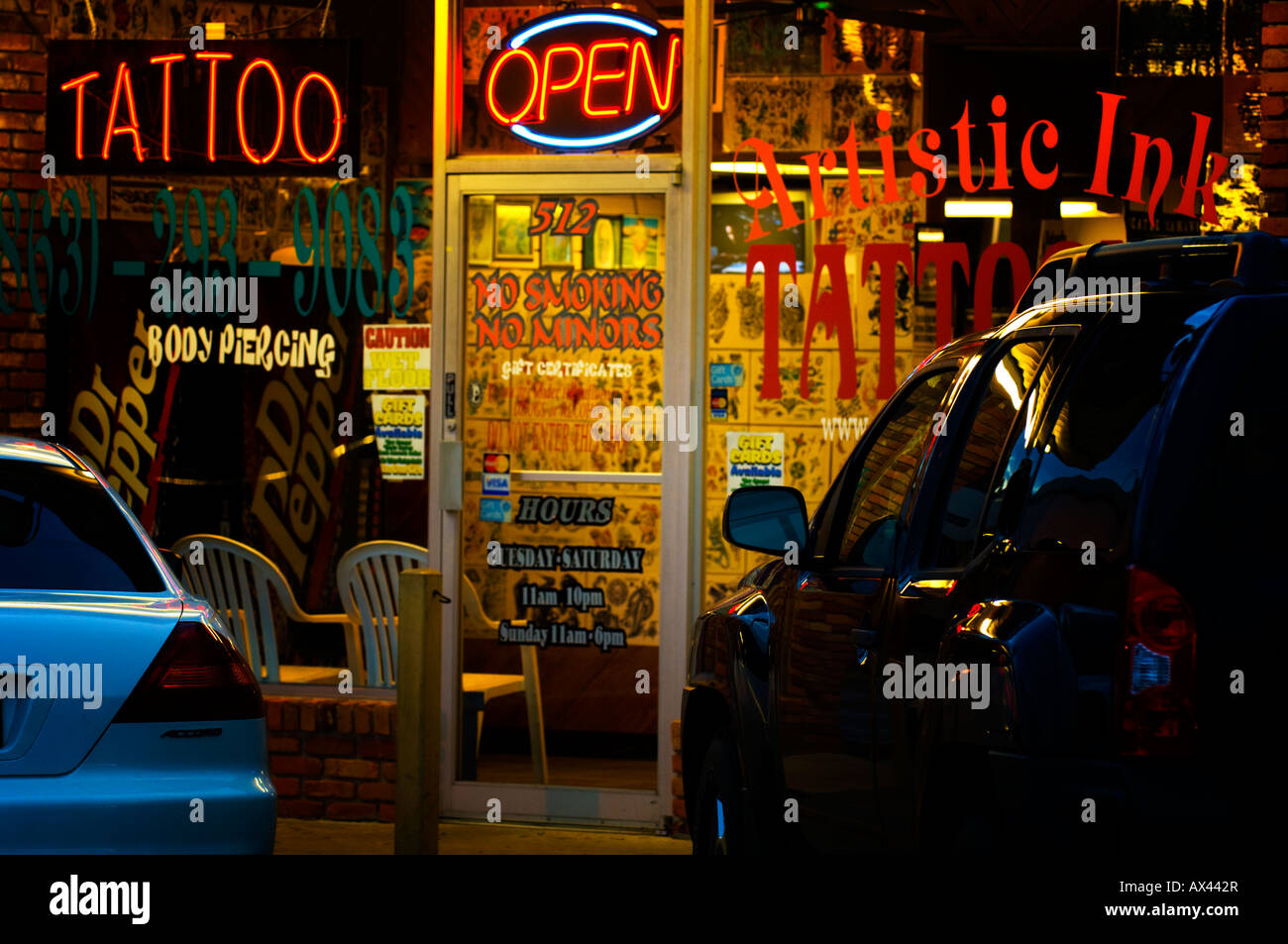 neon sign in tattoo parlor window in strip mall Stock Photo - Alamy