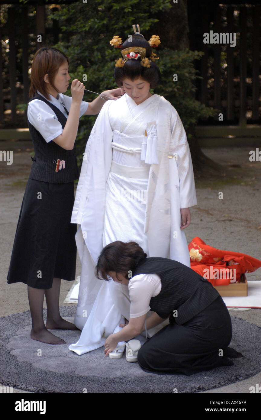 A bride s  wedding dress is adjusted before wedding photographs are taken at Meiji Jingu Shrine in Tokyo Japan Stock Photo