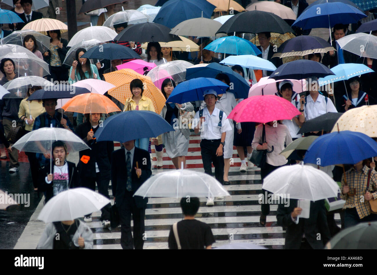 Crowds of workers make their way to work in the rain in Shibuya Tokyo Japan Stock Photo