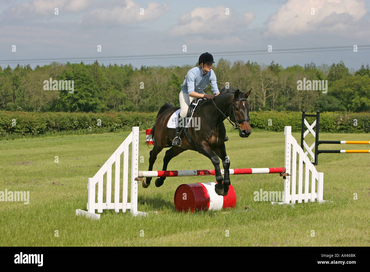 A Woman jumping her Horse in an outdoor riding school. Stock Photo