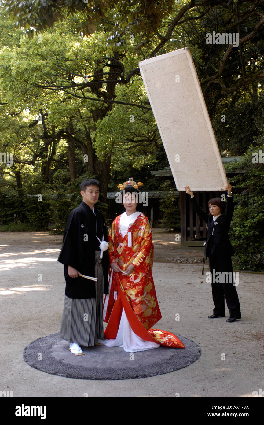 A bride and groom in traditional dress pose for wedding photographs at Meiji Jingu Shrine in Tokyo Japan Stock Photo