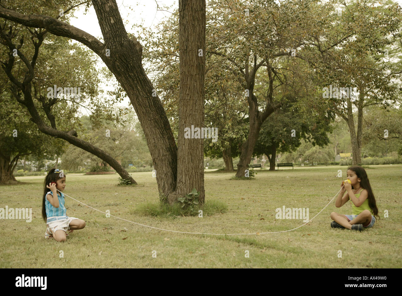 Side profile of girls talking on a toy phone in a park Stock Photo