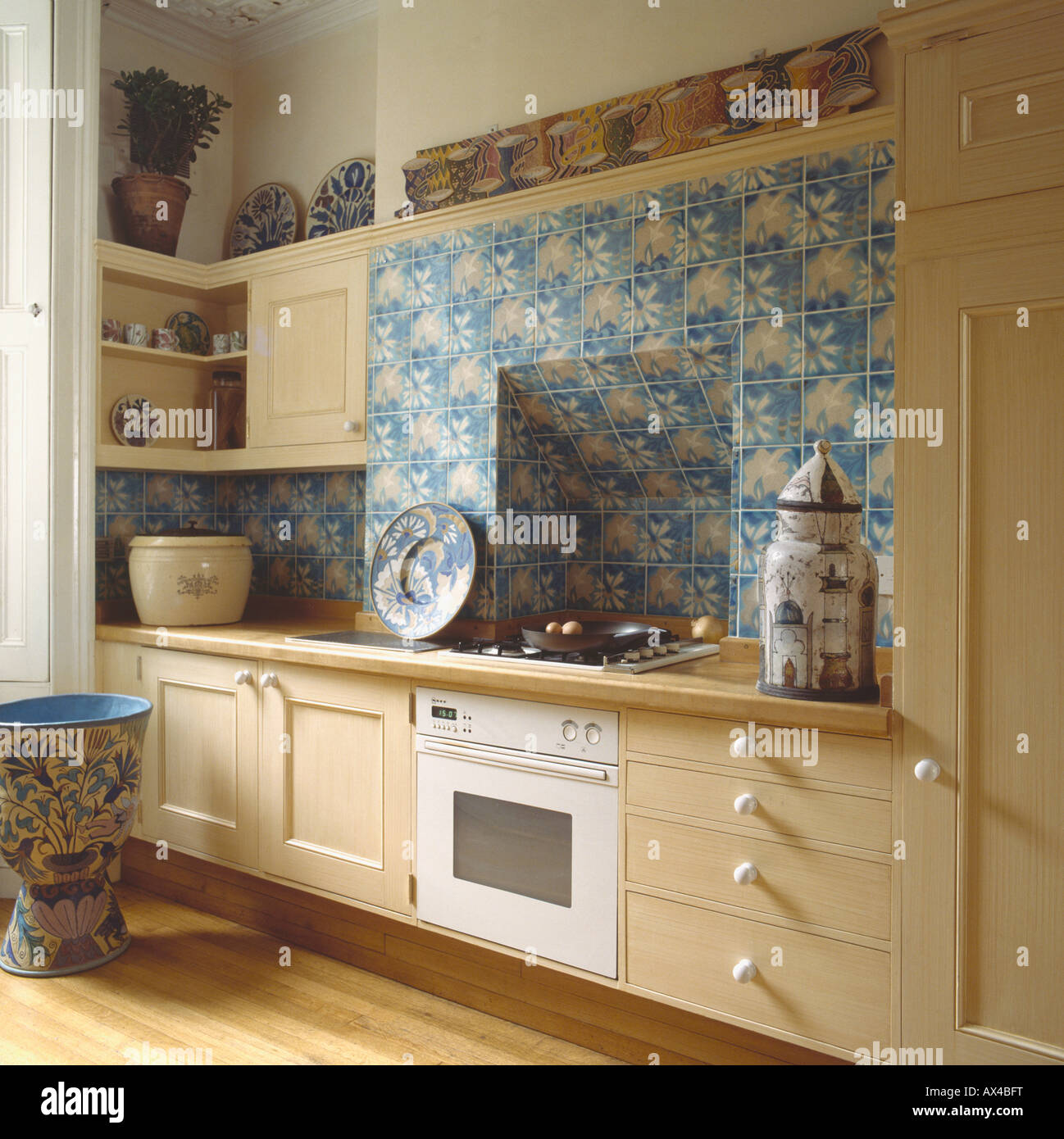 Blue floral tiles above white built in oven in neutral eighties kitchen